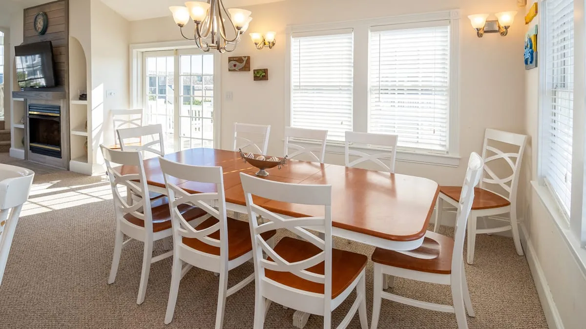 Un comedor luminoso con una mesa larga de madera y sillas blancas.