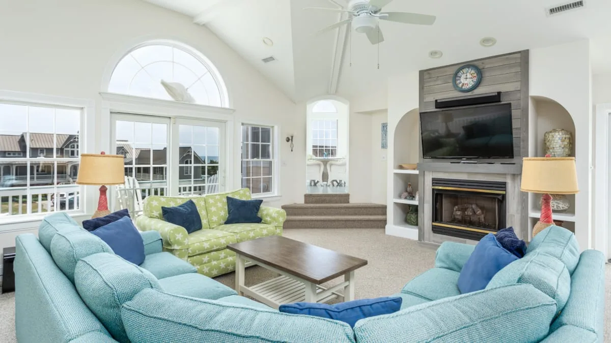 Una sala luminosa con asientos azules, una chimenea y un televisor.