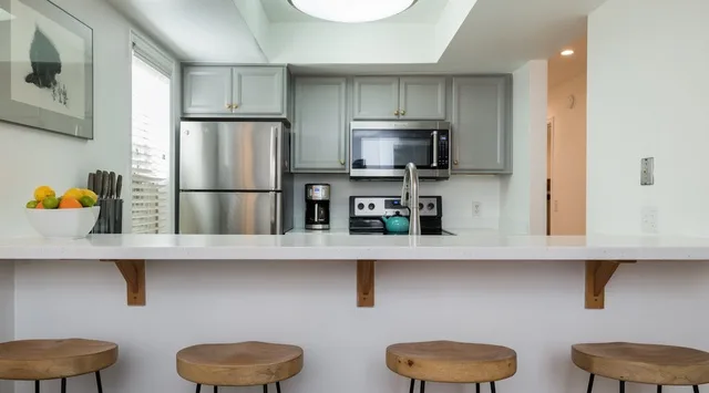 Una cocina con electrodomésticos de acero inoxidable y una barra con asientos.