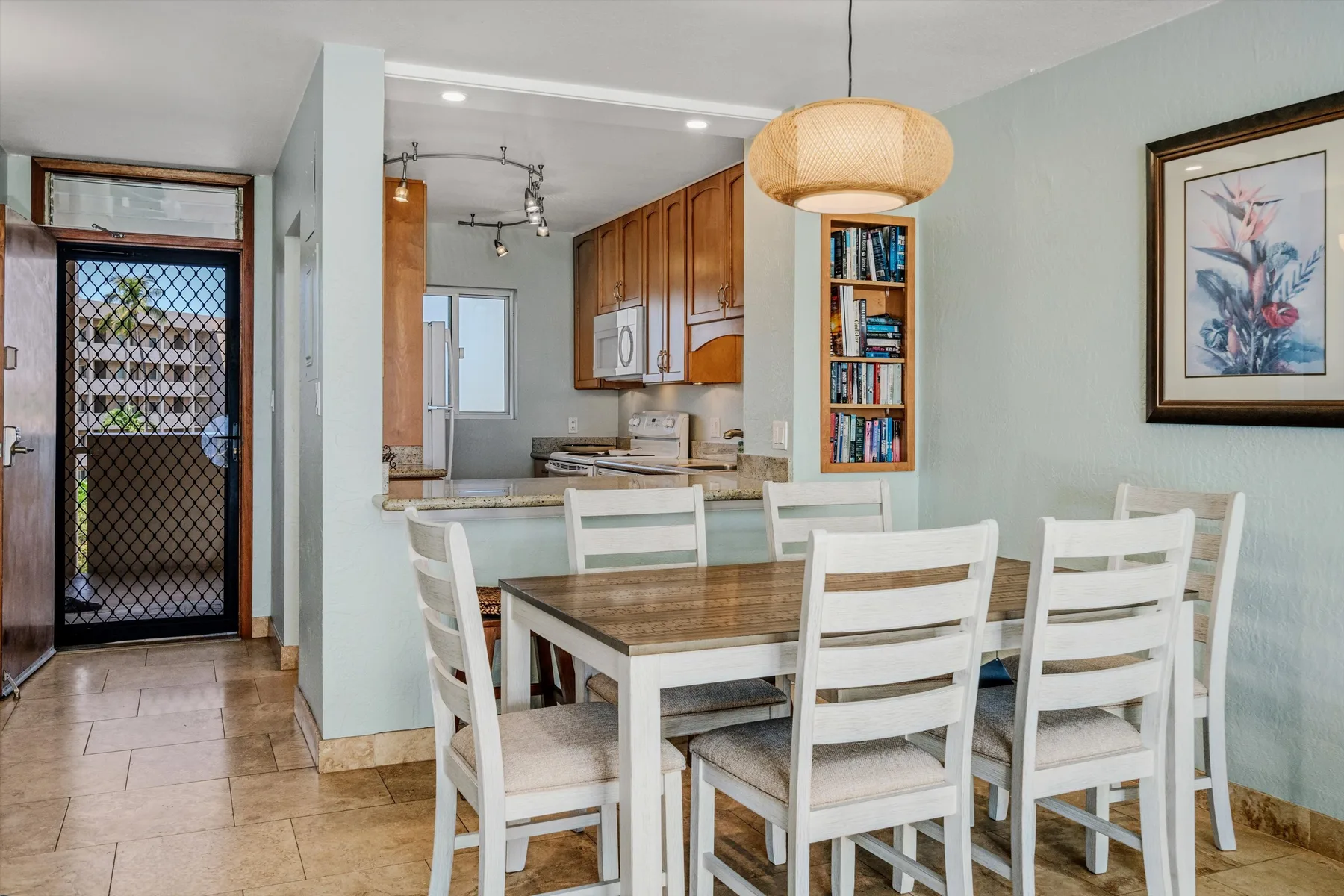 Comedor con asientos blancos junto a una cocina abierta y una estantería empotrada.