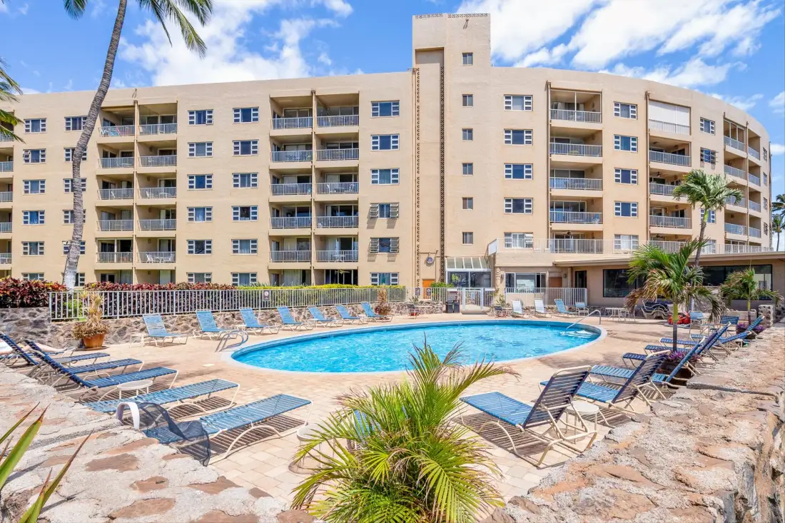 Una piscina al aire libre y asientos alrededor están frente a un edificio de varios pisos.
