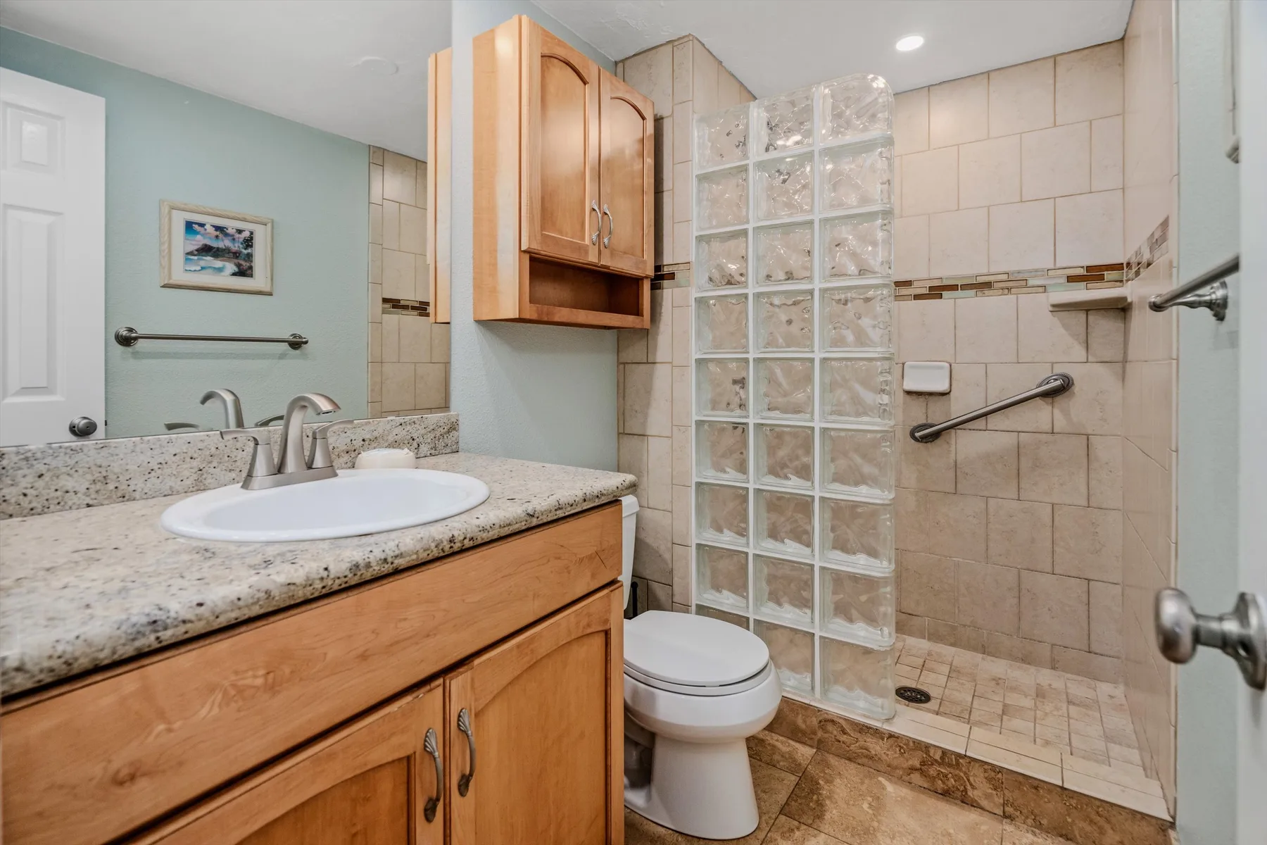 Un baño con lavabo y mueble, inodoro y zona de ducha con azulejos.