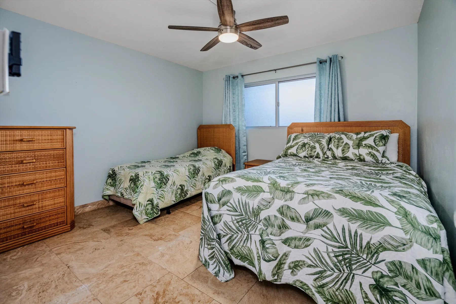 Un dormitorio con dos camas vestidas con ropa de cama de hojas verdes.