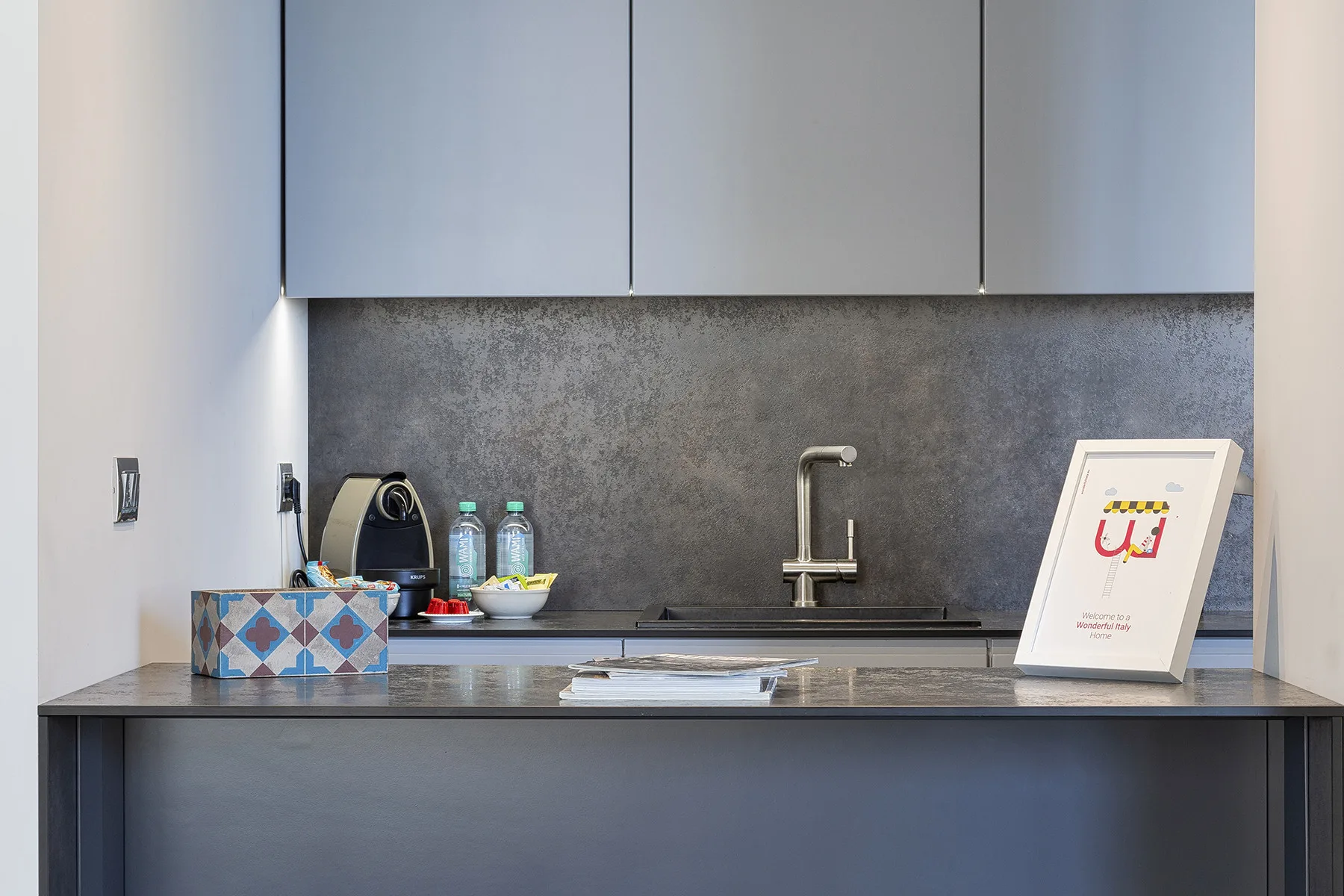 Una encimera de cocina moderna con fregadero, cafetera y bebidas.