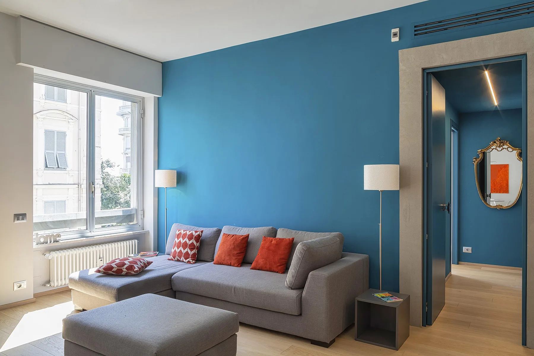 Una sala de estar con un sofá seccional gris y paredes azules.