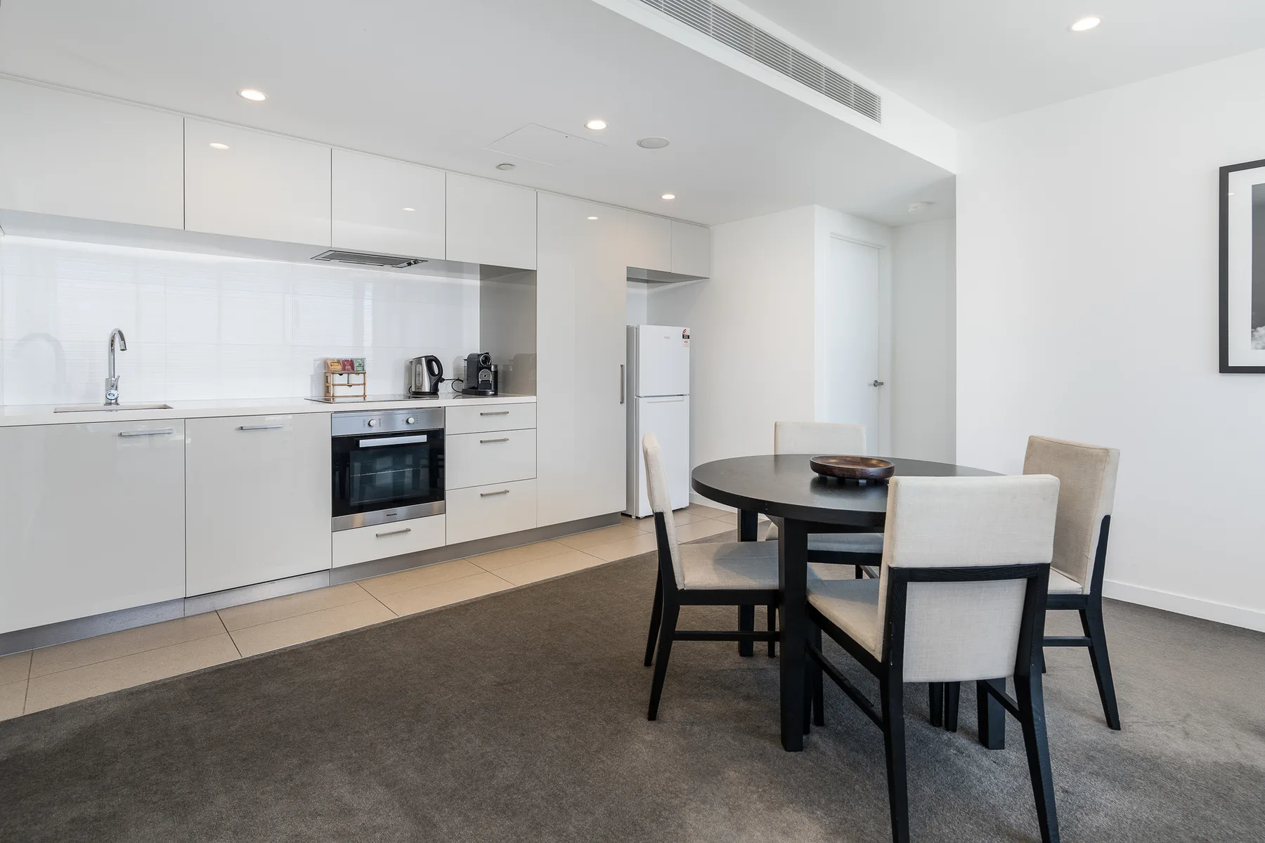 A bright kitchen and dining area with white cabinetry and a table.