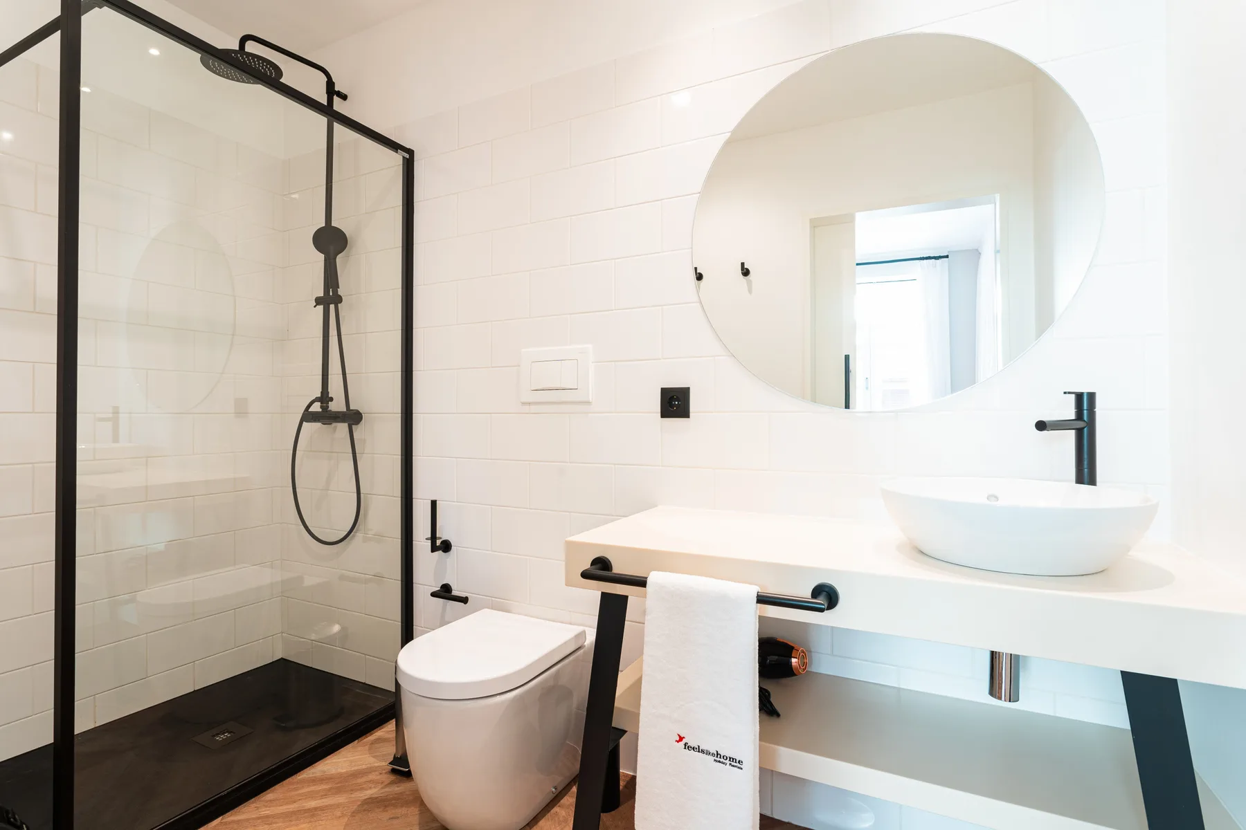Un baño luminoso con ducha de cristal, inodoro y lavabo.