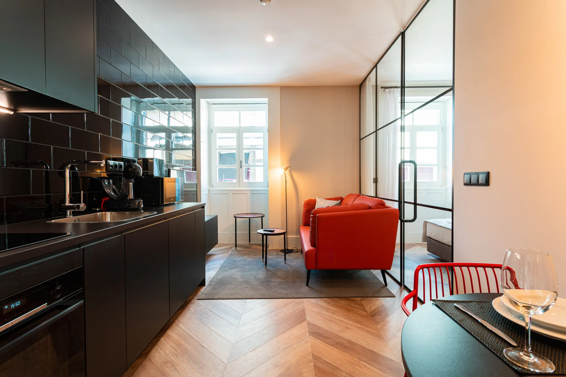 Sala de estar y cocina de concepto abierto, con asientos rojos y muebles oscuros.