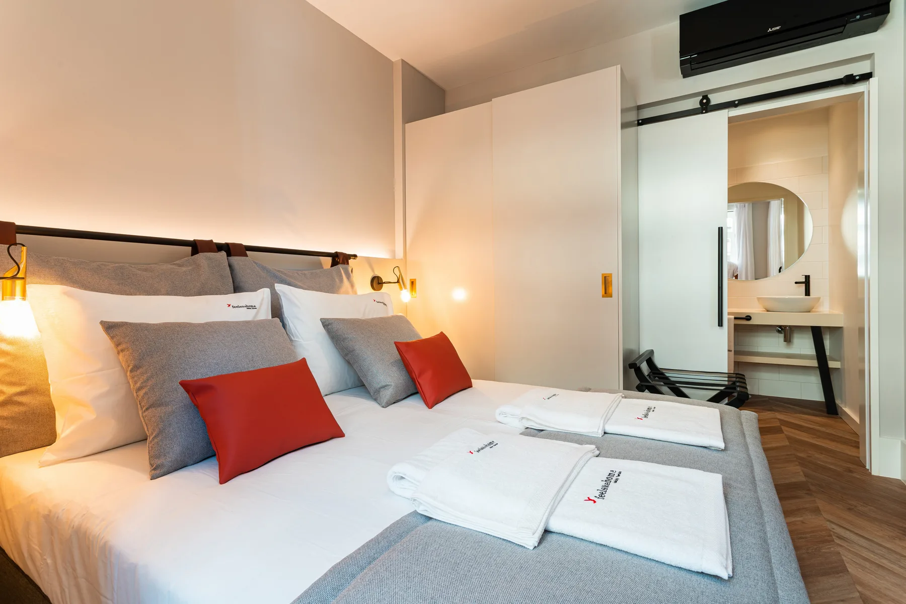 Un dormitorio con una cama bien tendida y una puerta abierta al baño.