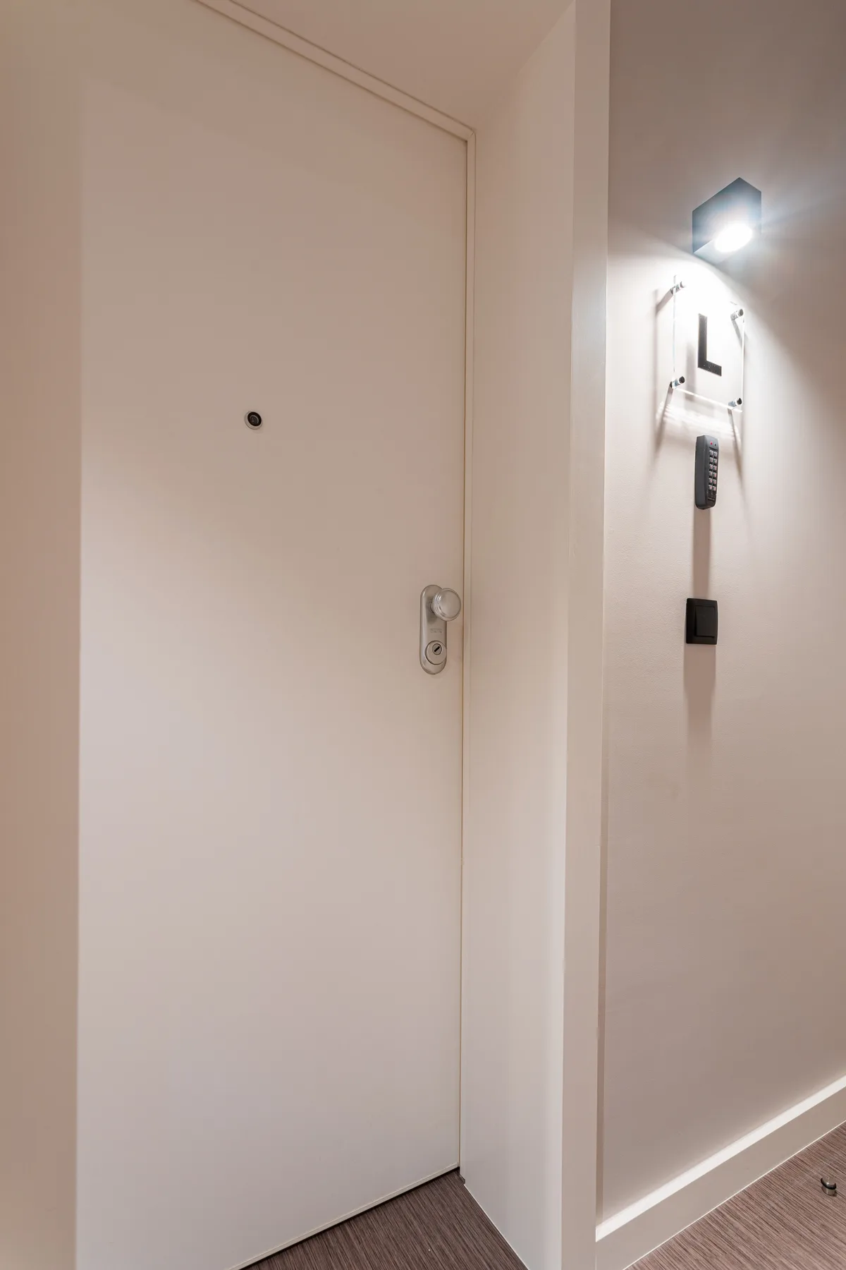 Una puerta blanca da a un pasillo interior bien iluminado.