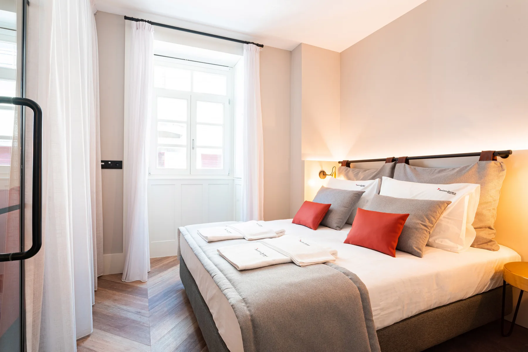 Un dormitorio con una cama bien tendida y ventanas luminosas.