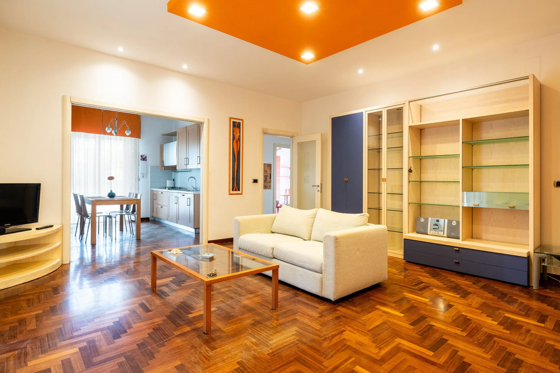 Una sala luminosa con un sofá color crema y estanterías empotradas.