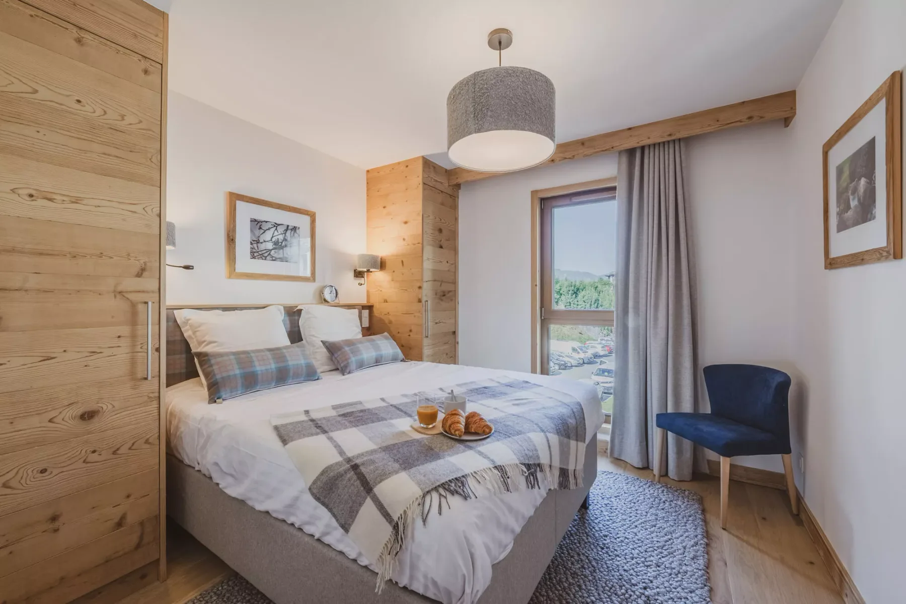 Dormitorio con cama doble, ropa de cama a cuadros y un sillón azul.
