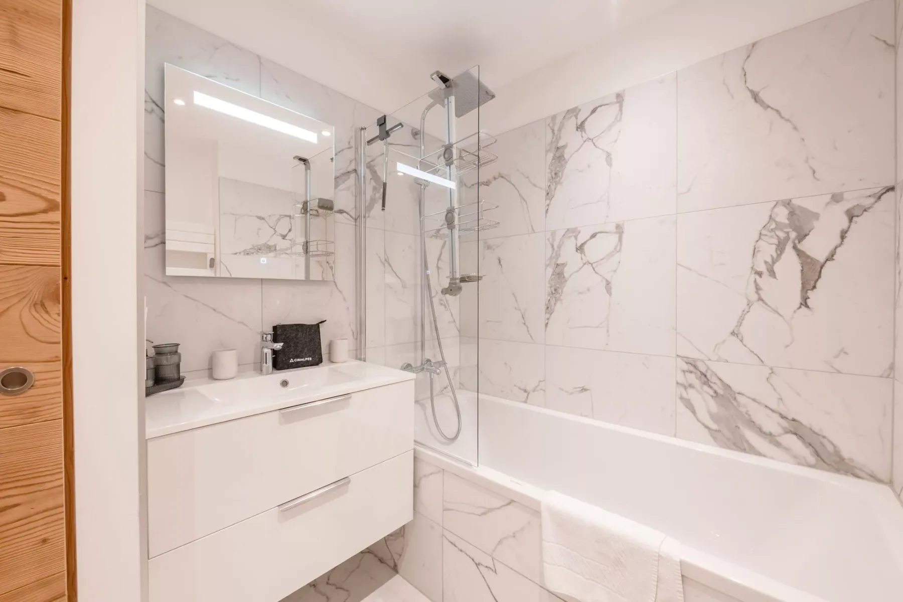 Un baño luminoso con bañera, mampara de vidrio y tocador blanco.