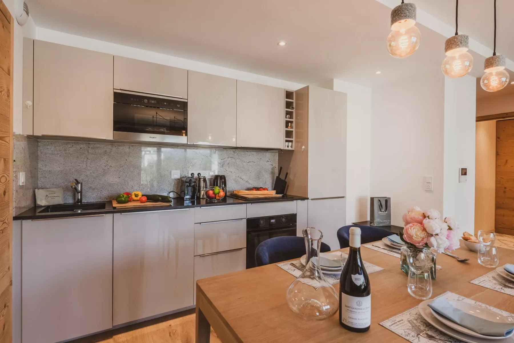 Una cocina moderna se abre a un comedor con la mesa puesta.
