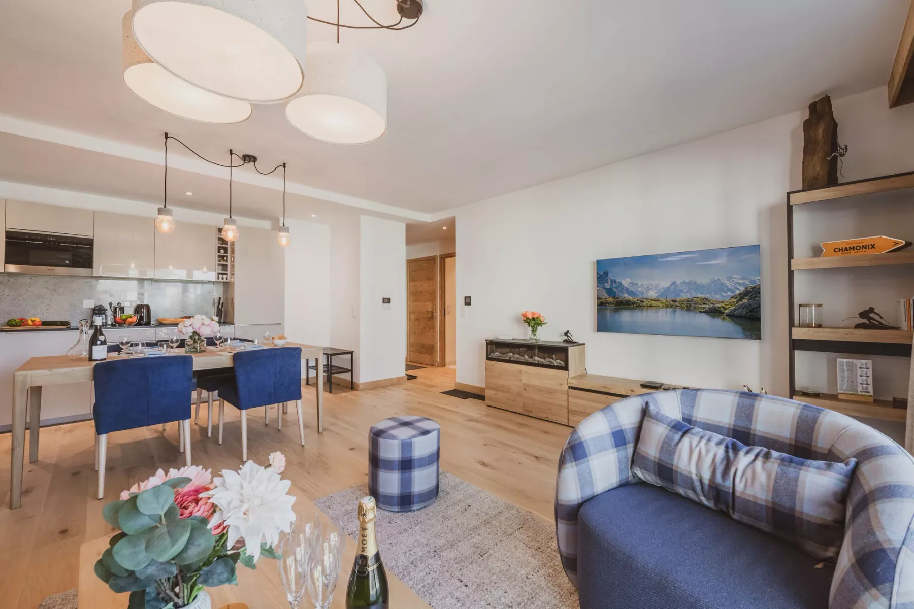 An open-plan living room and kitchen with a plaid sofa and dining area.