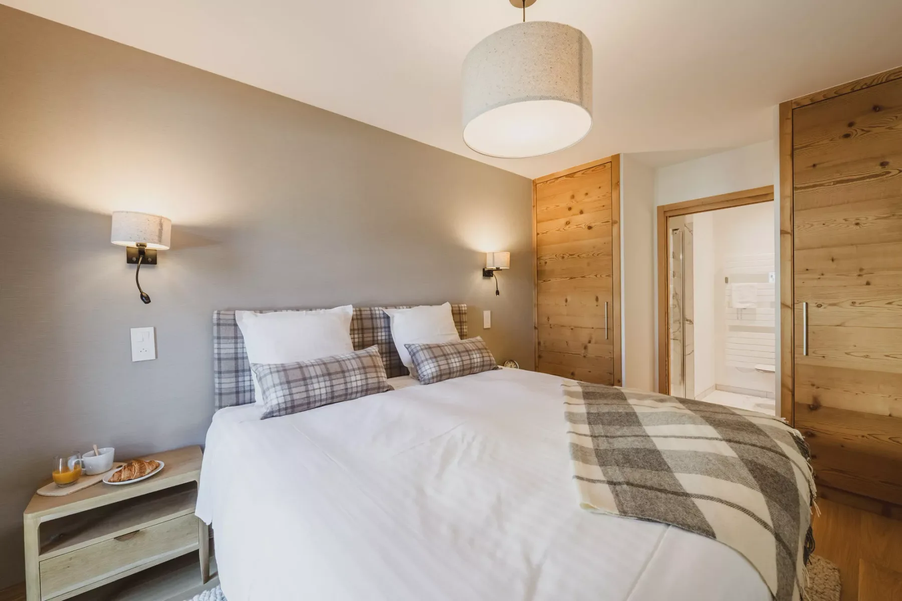 Un dormitorio con una cama bien tendida y ropa de cama a cuadros.