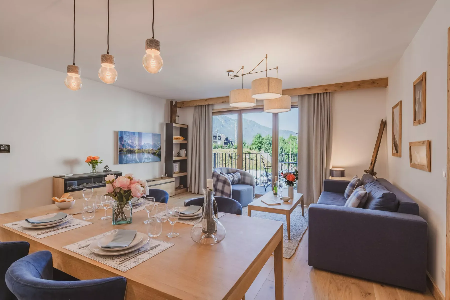 A dining and living area opens onto a balcony, with a set table and seating.