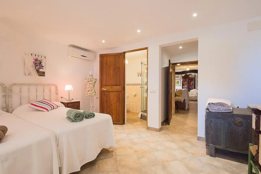 Un dormitorio luminoso con dos camas, un armario de madera y una puerta abierta.