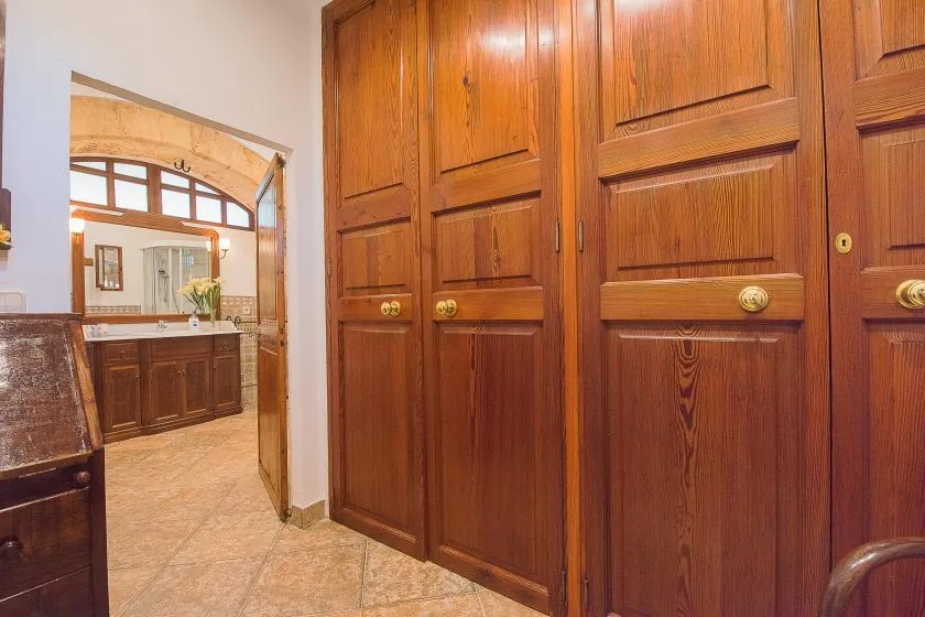 Un pasillo interior con paneles de madera da a una zona de lavabo.