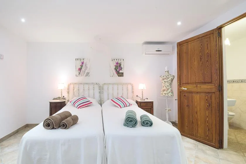 Un dormitorio luminoso con dos camas individuales y un armario de madera.