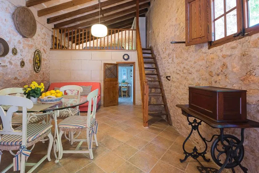 Un comedor rústico con una escalera de madera y paredes de piedra.