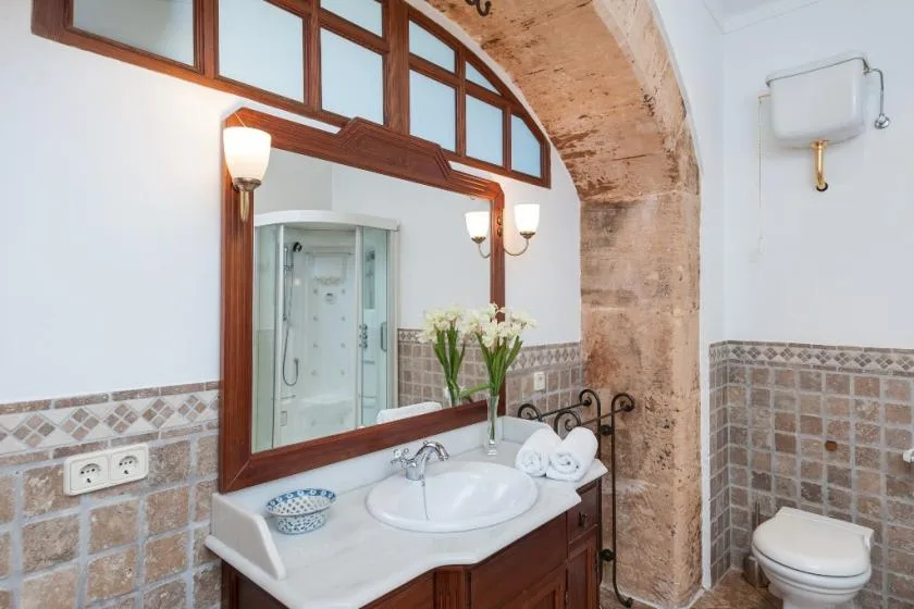 Un baño con lavabo, espejo grande y ducha.