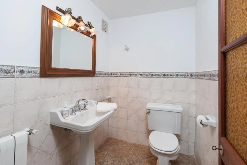 Un baño con azulejos, lavabo, espejo e inodoro.