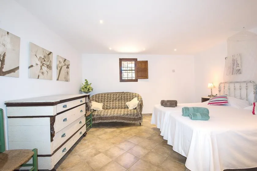 Dormitorio con una cama, una pequeña zona de estar y una cómoda.