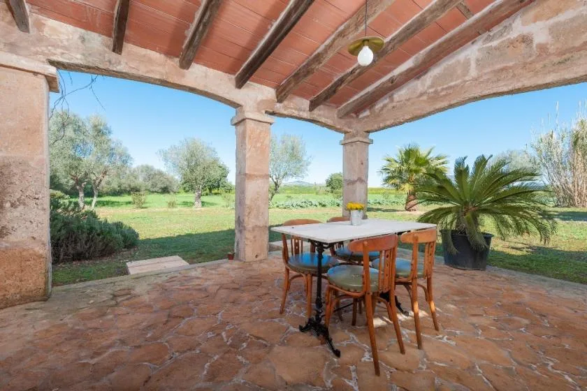 Un patio cubierto con una mesa de comedor da a un jardín verde.