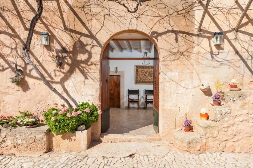 Una entrada arqueada se abre a una habitación con muebles de madera y arte enmarcado.