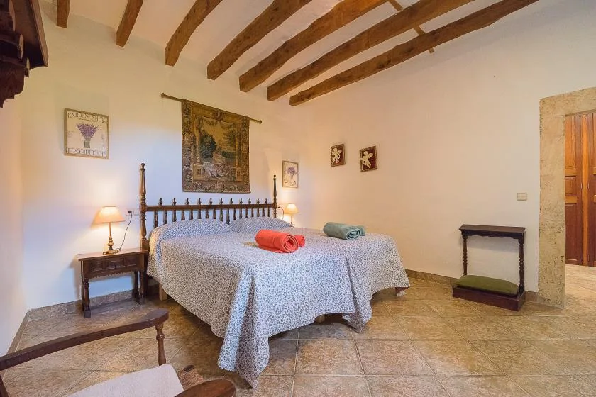 Un dormitorio con una cama grande bajo vigas de madera expuestas en el techo.