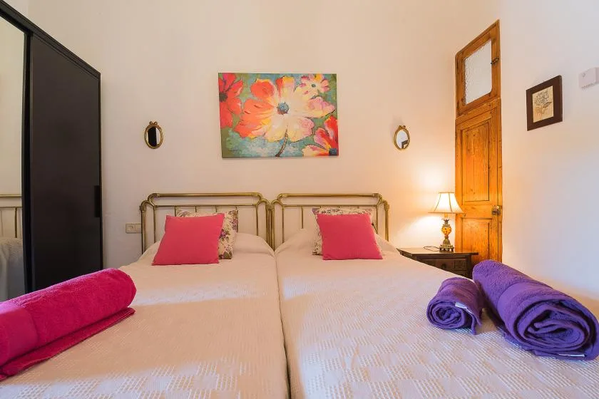 Un dormitorio con dos camas, arte colorido en la pared y una lámpara de noche.