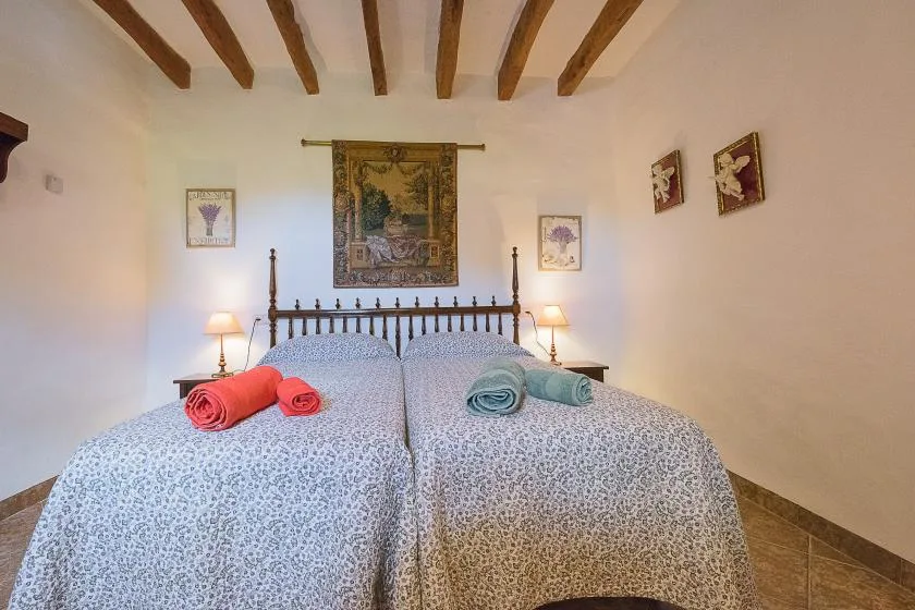 Un dormitorio con dos camas, ropa de cama estampada y vigas de madera en el techo.