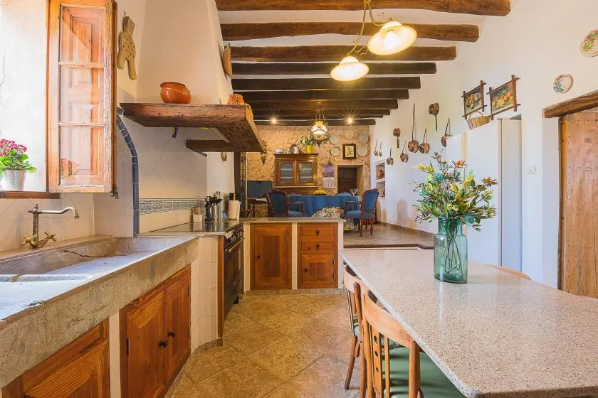 Una cocina y comedor de estilo rústico con vigas de madera y una mesa larga.