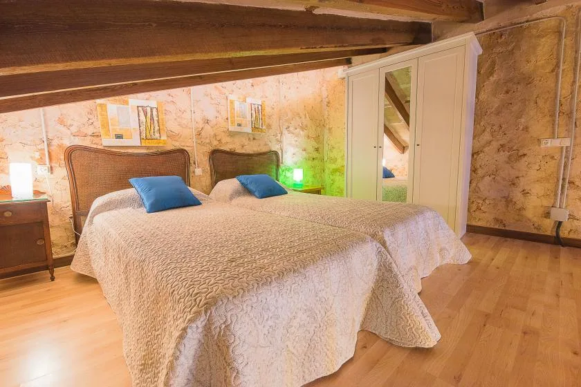 Un dormitorio con dos camas, almohadas azules y un armario con espejo.