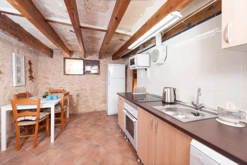Una cocina rústica con una mesa de comedor y vigas de madera a la vista.