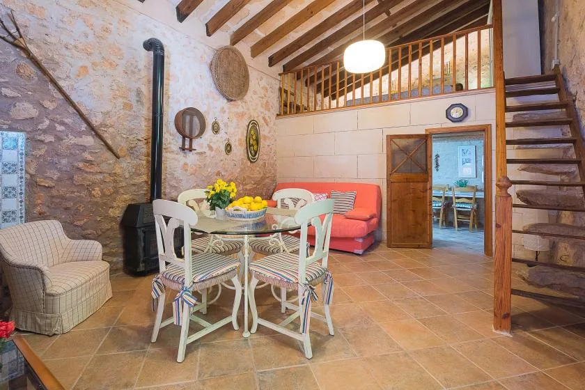 Una zona rústica de comedor y estar tiene una mesa, asientos y vigas de madera expuestas.