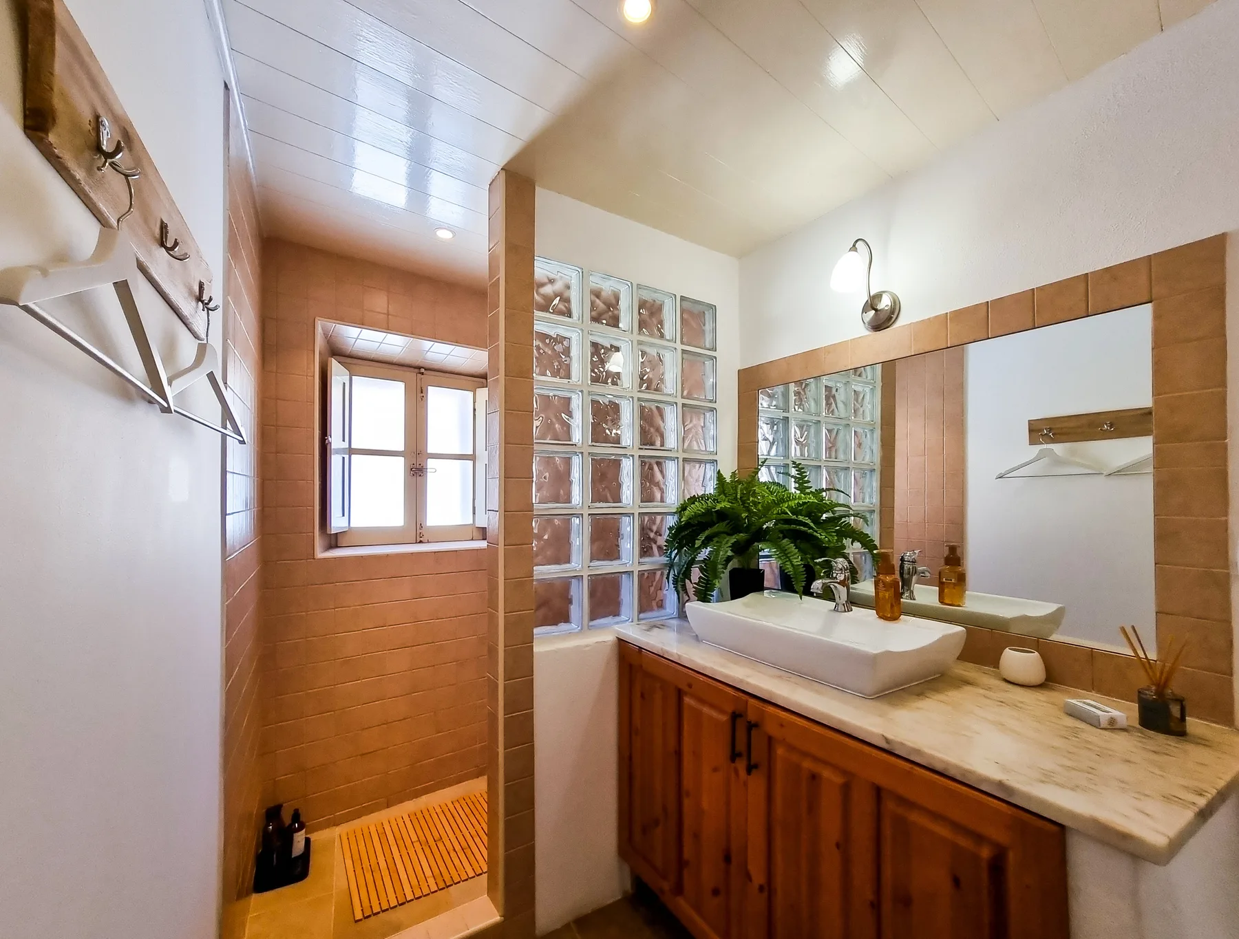 A bathroom vanity with a sink and mirror beside a tiled shower area.
