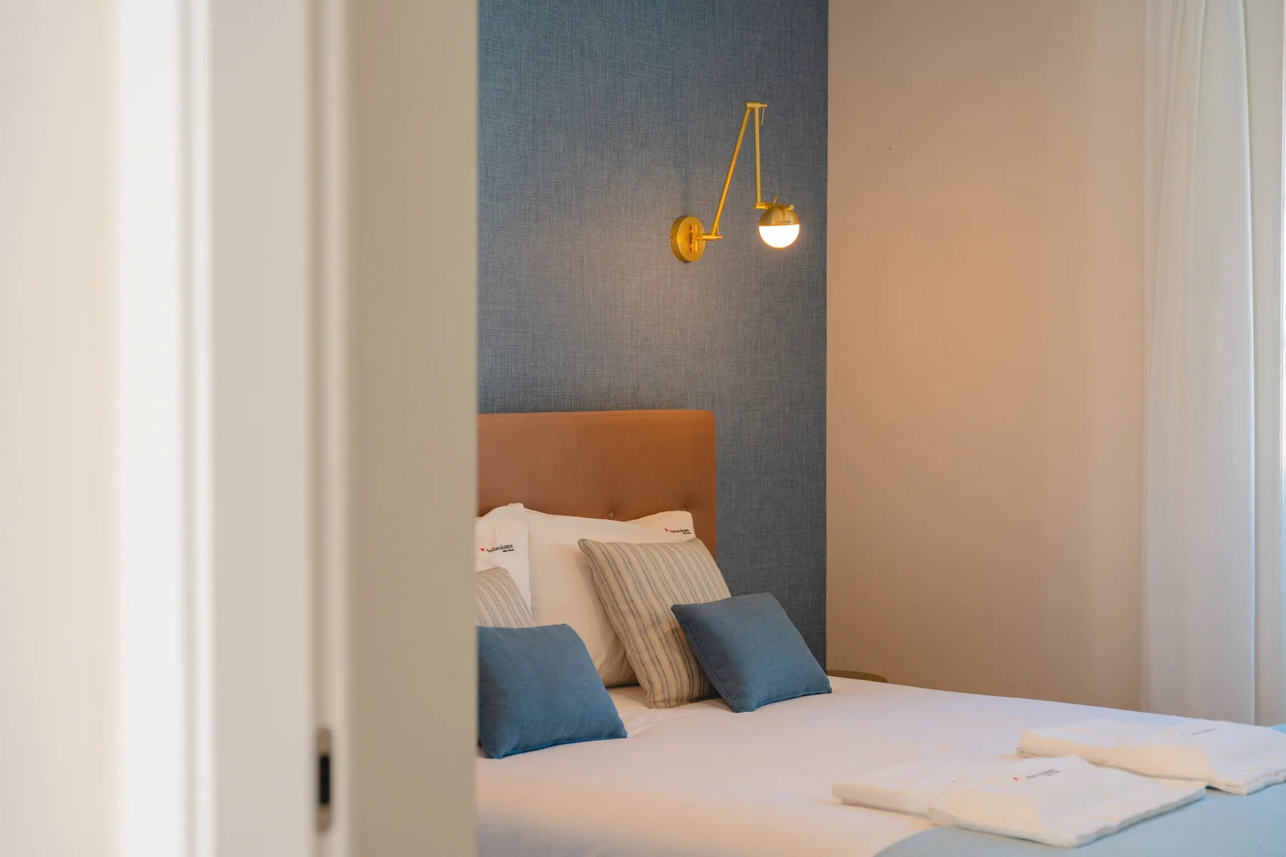 Un dormitorio con una cama bien tendida y cojines azules.