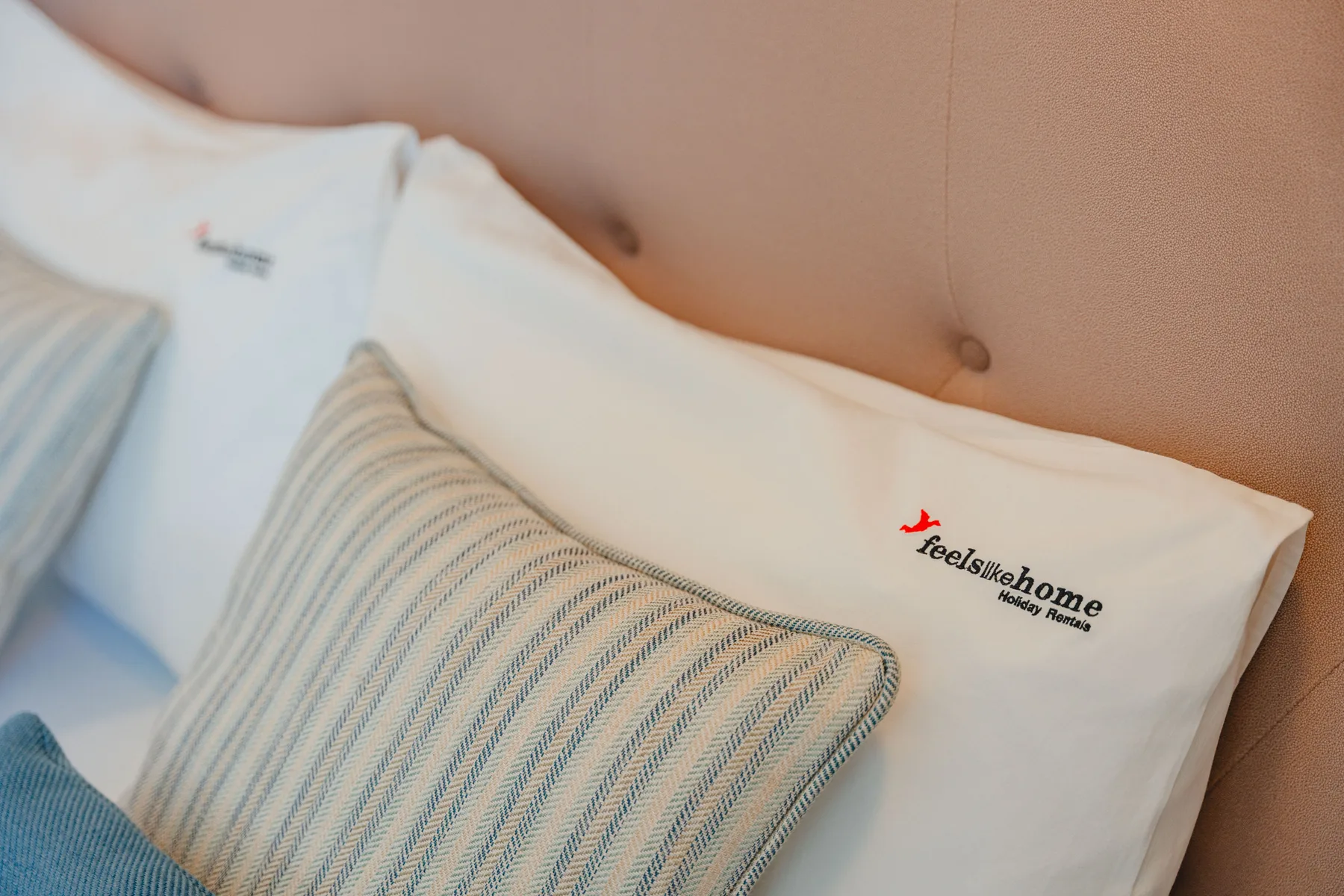 Dormitorio con ropa de cama blanca y un cojín decorativo a rayas.