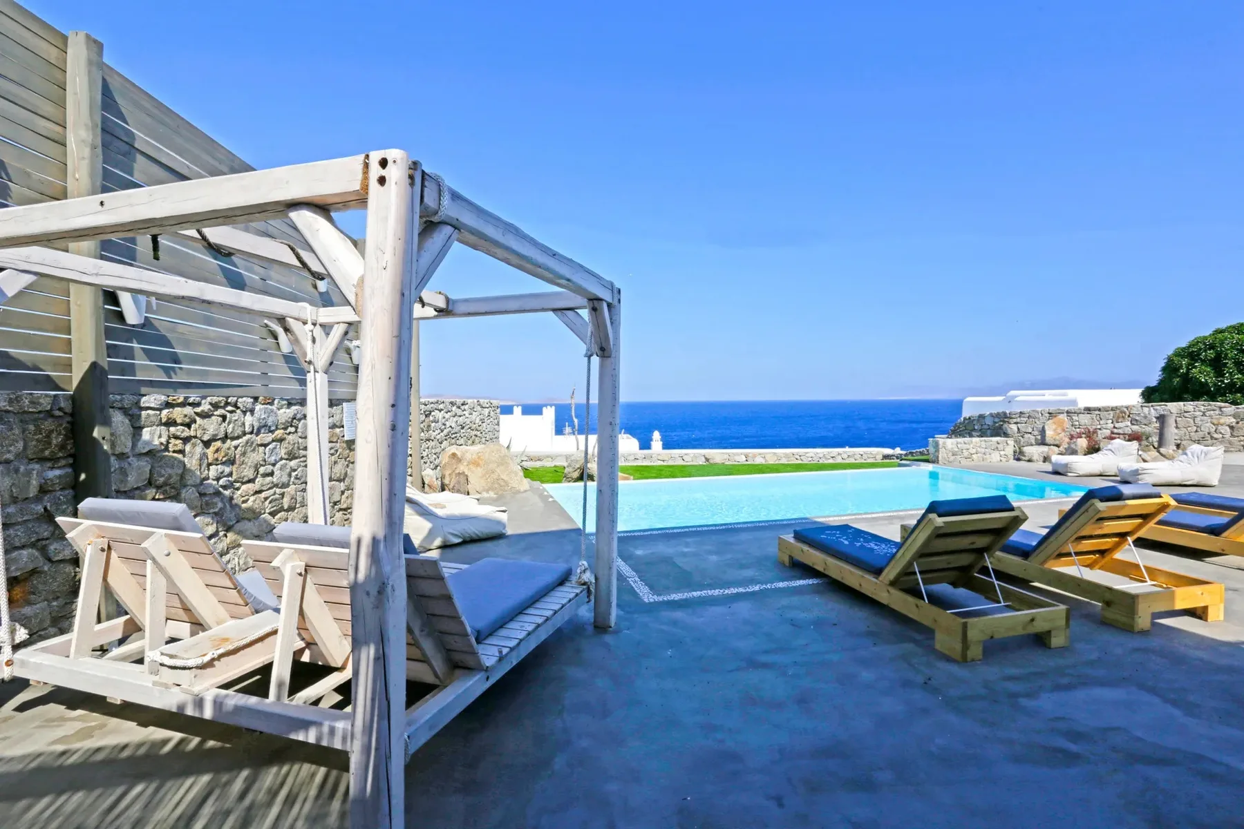 A poolside terrace has lounge seating and views of the sea.