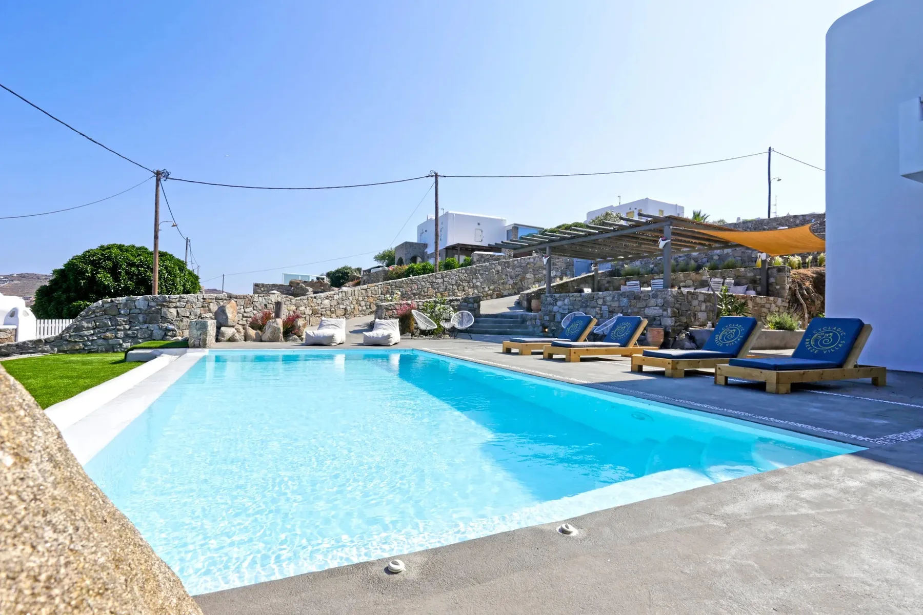 An outdoor swimming pool is bordered by stone walls and blue lounge seating.
