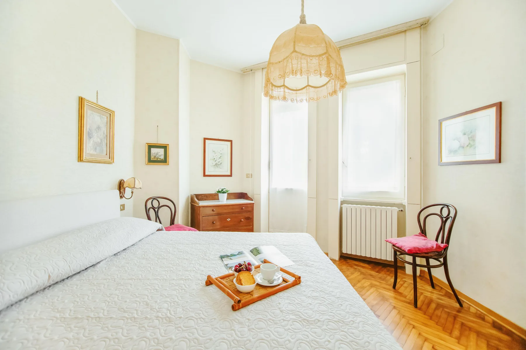 A bright bedroom with a bed, a window, and a small seating area.