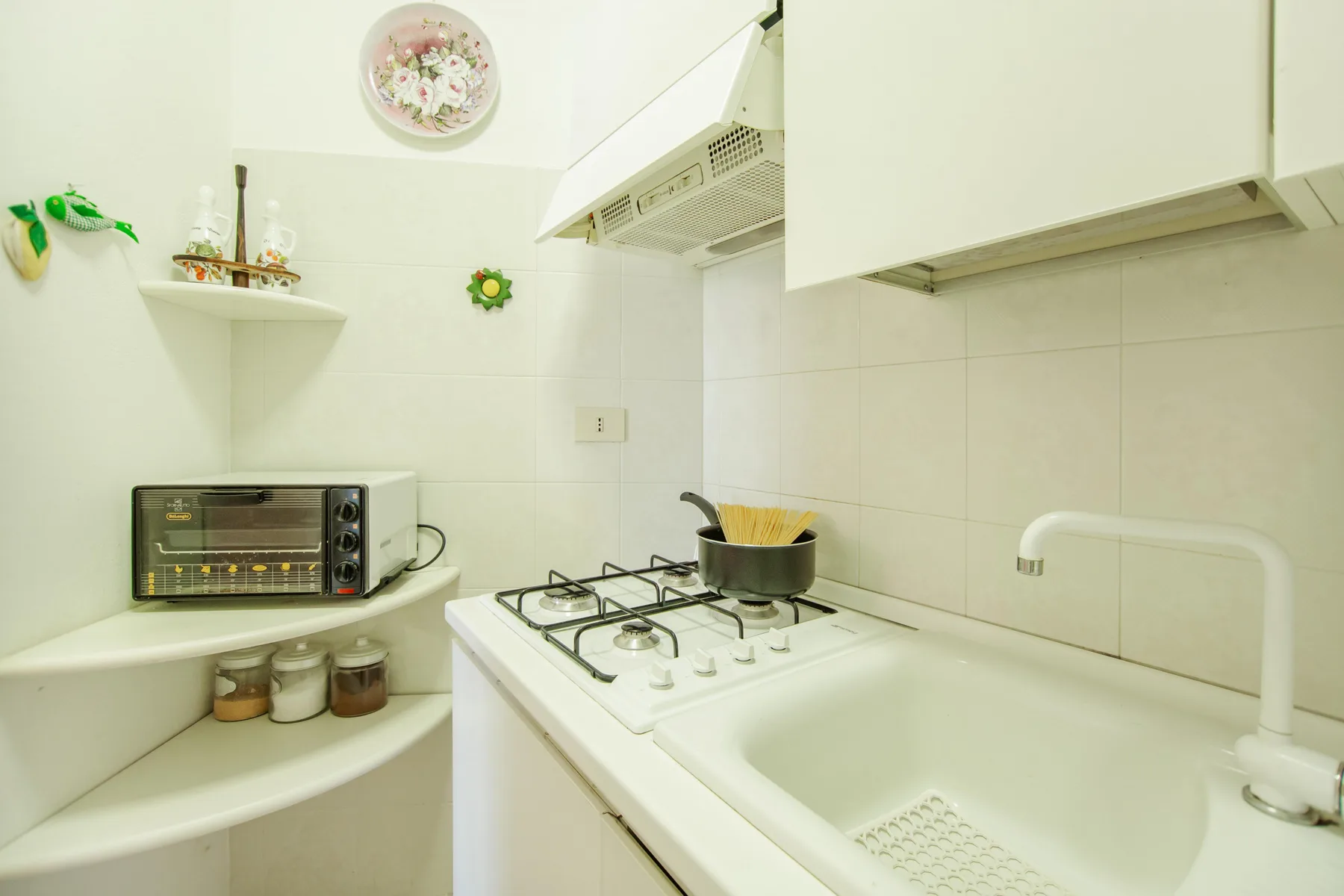 A compact kitchen with a gas cooktop, sink, and countertop oven.