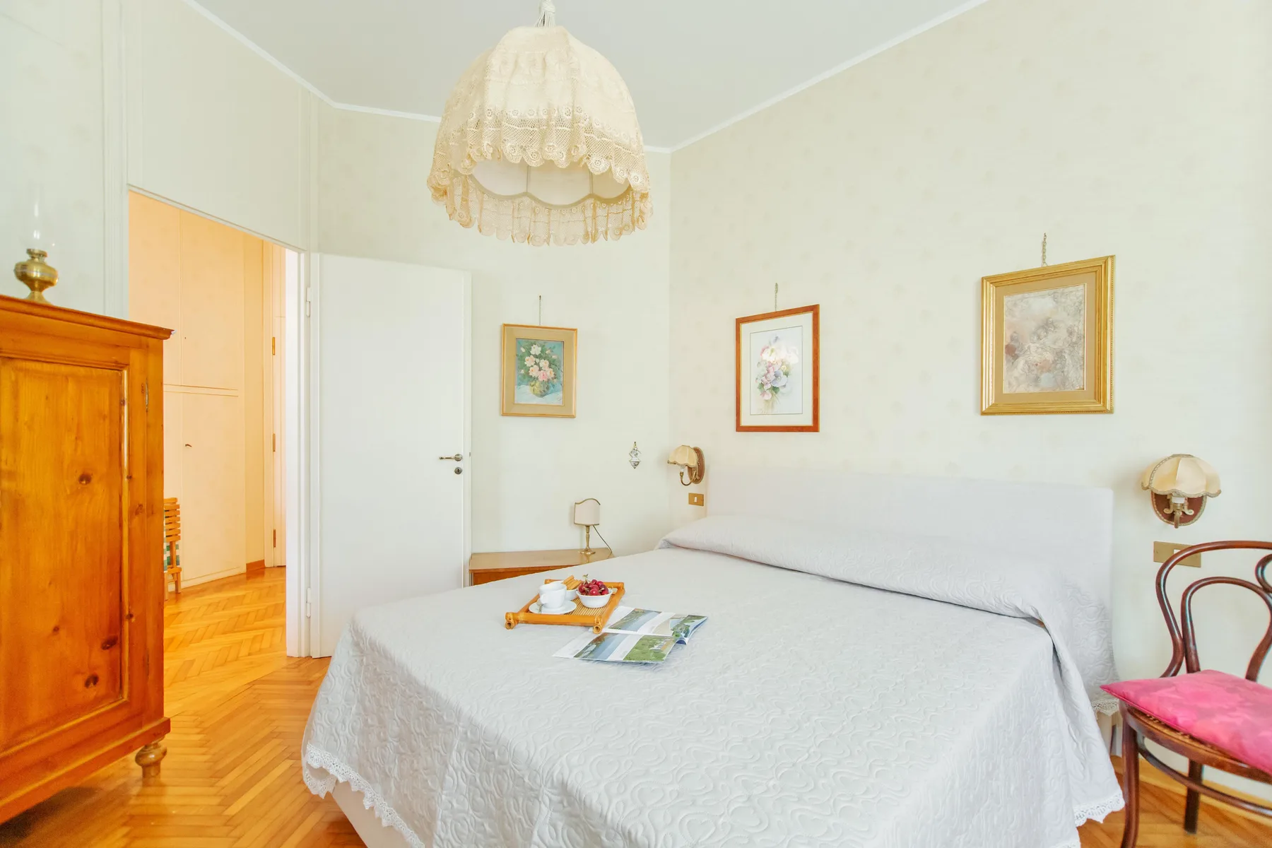 A bright bedroom with a neatly made bed and framed pictures on the walls.