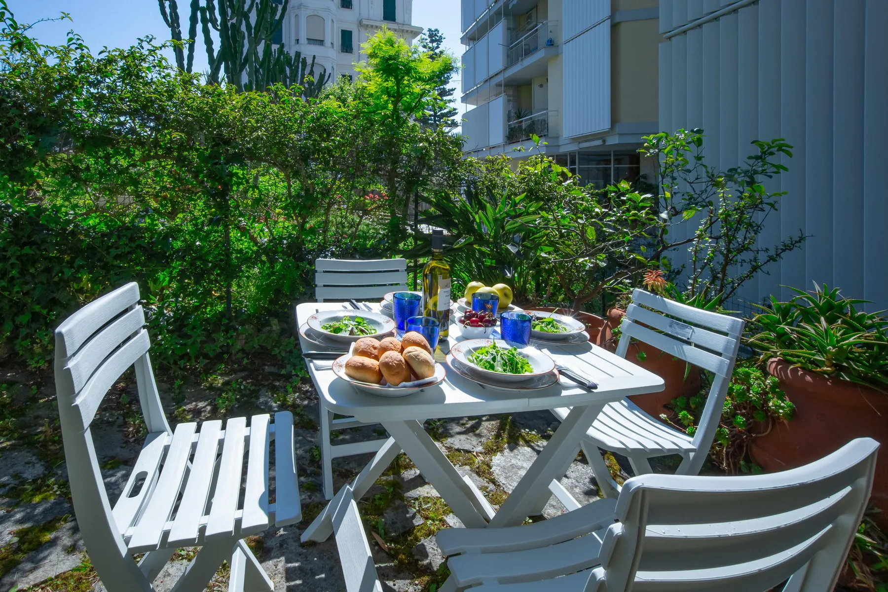 An outdoor dining area with a table set among leafy plants.
