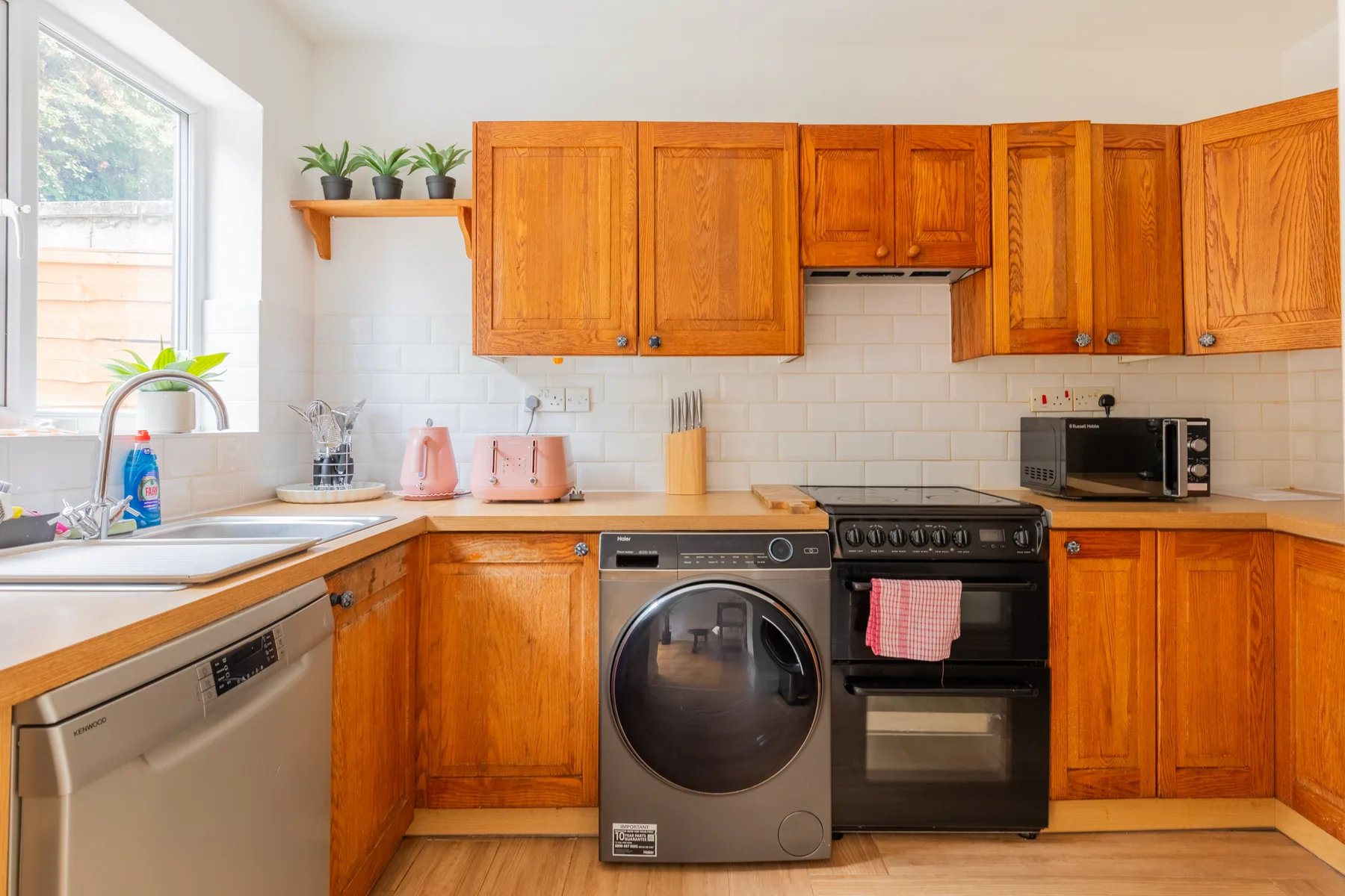 Una cocina con armarios de madera, una lavadora y un horno.