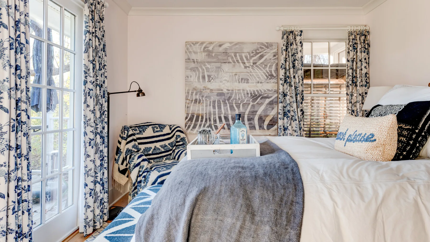 Un dormitorio con una cama arreglada y cortinas estampadas.