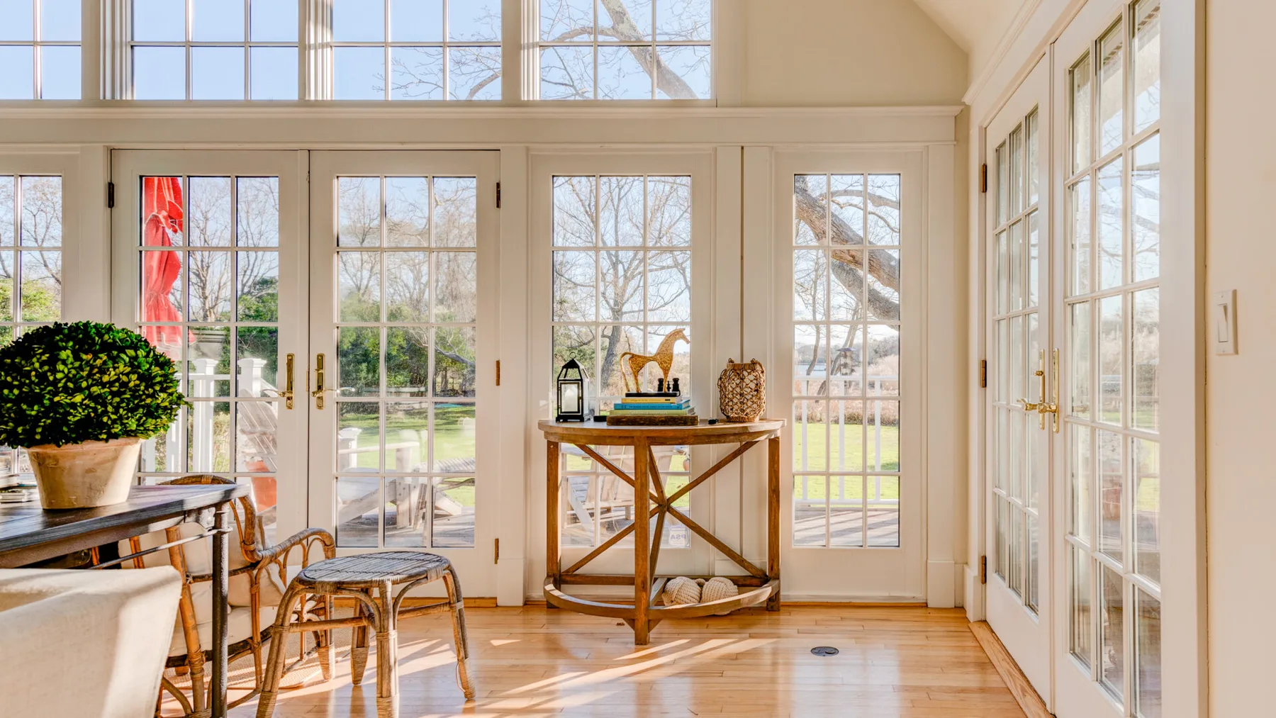 Un solárium luminoso con grandes ventanas y una mesa pequeña.